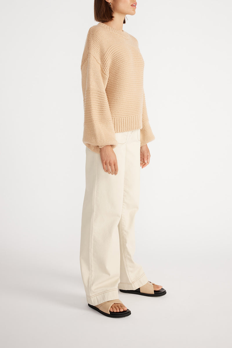 Side view of woman wearing Ana Oversized Jumper with cream wide leg jeans.