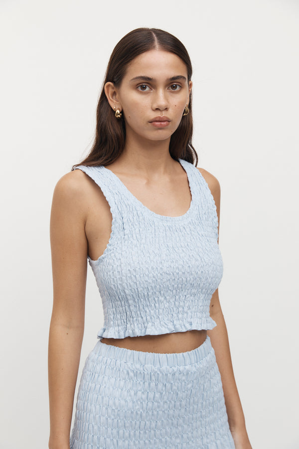 Close up view of woman wearing Eze Shirred Linen Crop Top in sky.