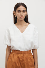 Woman wearing Giverny Puff Sleeve Top in white with burnt orange shorts.