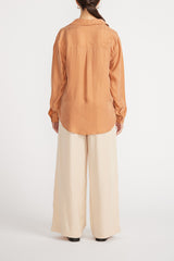 Rear view of woman wearing Elsie Cupro Shirt with wide leg pants.
