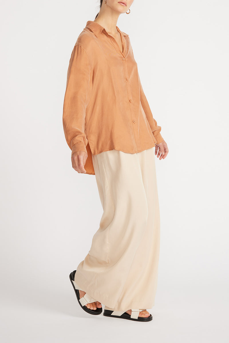 Side view of woman wearing Elsie Cupro Shirt in ginger with wide leg pants.