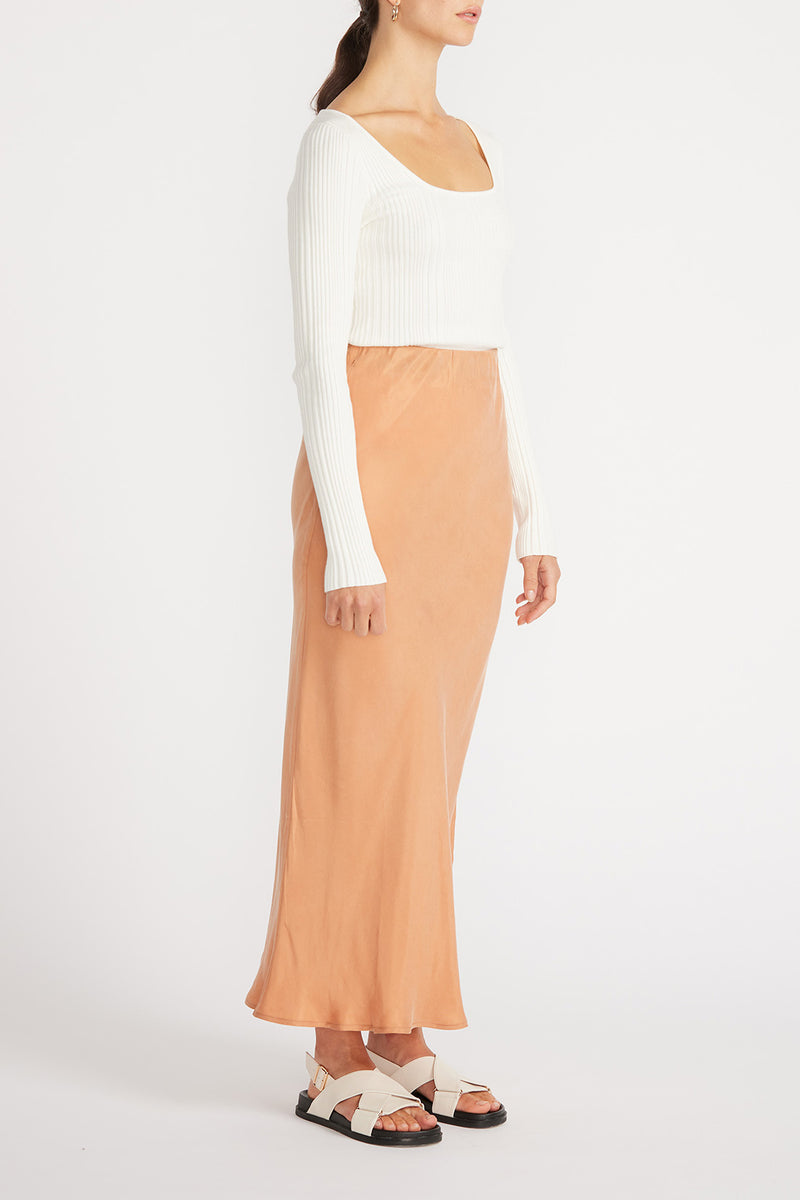 Side view of woman in white top and Elsie Cupro Skirt in Ginger.