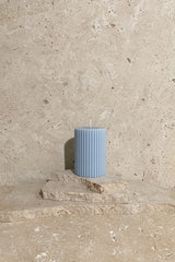 Ribbed pillar candle blue on stack of travertine