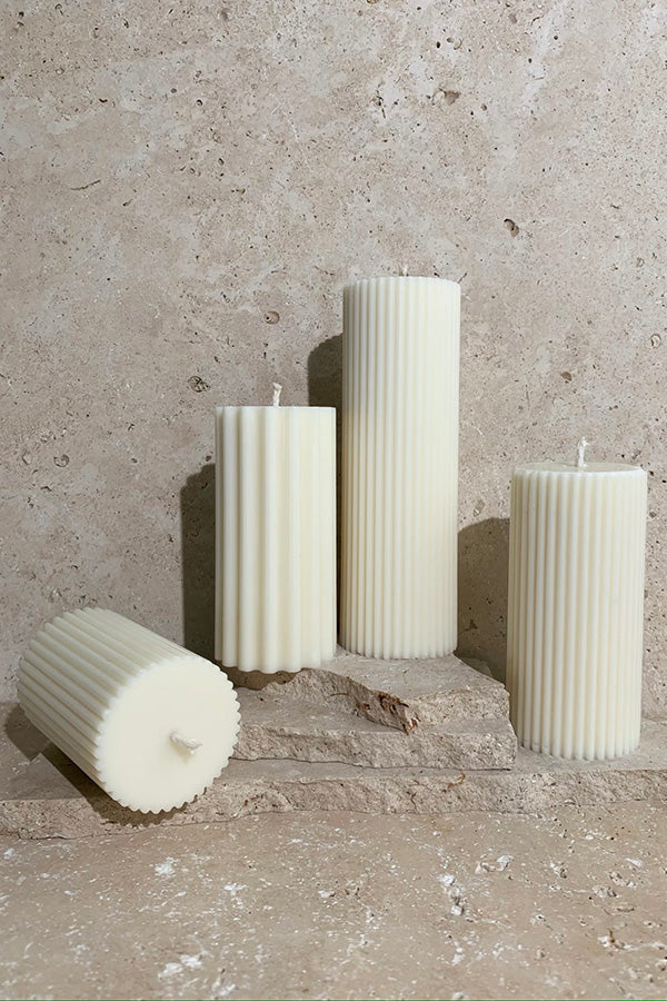 Group of various sized candles on stack of travertine