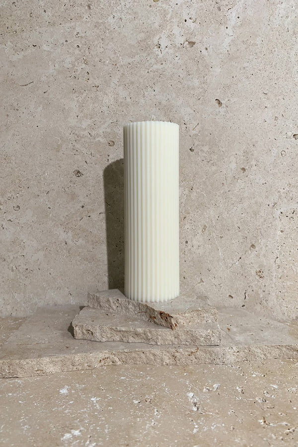 Ribbed pillar candle cream on travertine stack