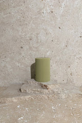 Ribbed pillar candle green on stack of travertine