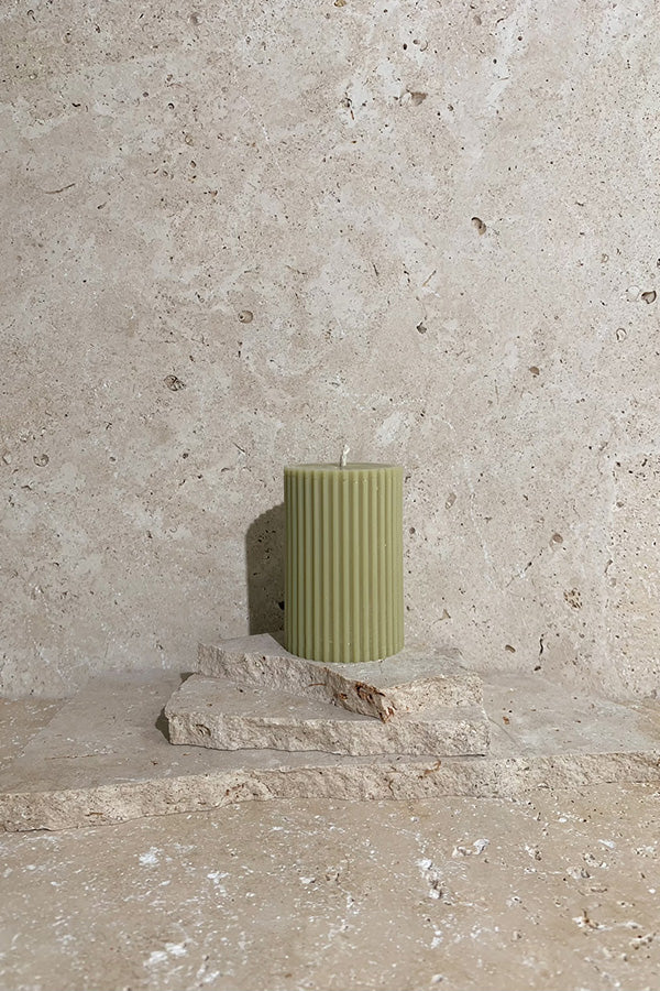 Ribbed pillar candle green on travertine stack